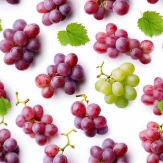A beautiful pattern of green and purple grapes with leaves on a white background